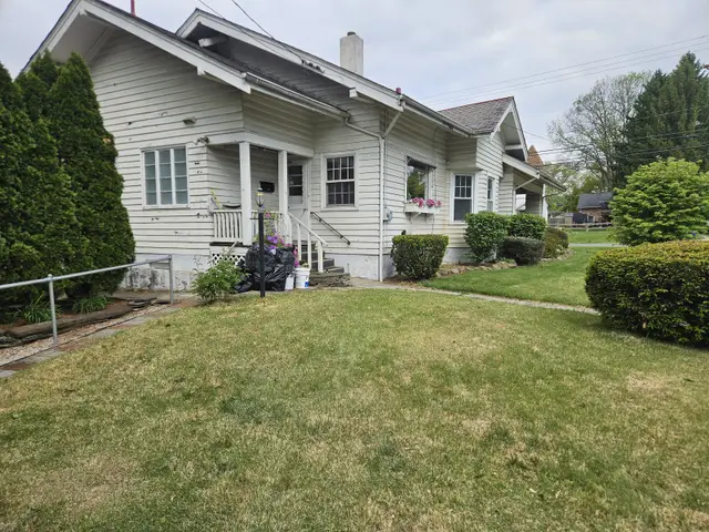 A gray craftsman bungalow with a front porch, white trim and a deep green lawn.