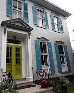 Historic exterior repaint with crisp white brick, blue shutters, and a bold accent door - exterior painting.
