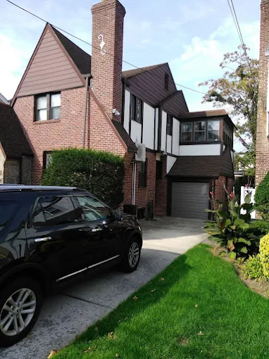 Tudor-style home exterior — freshly painted dark trim and timber detailing against classic brick. Exterior painting.