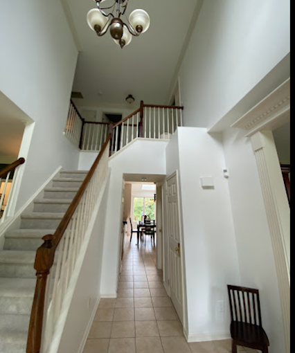 Two-story entry foyer — tall, flawless white walls with detailed trim and crown moulding. Interior painting & smooth-wall finish.