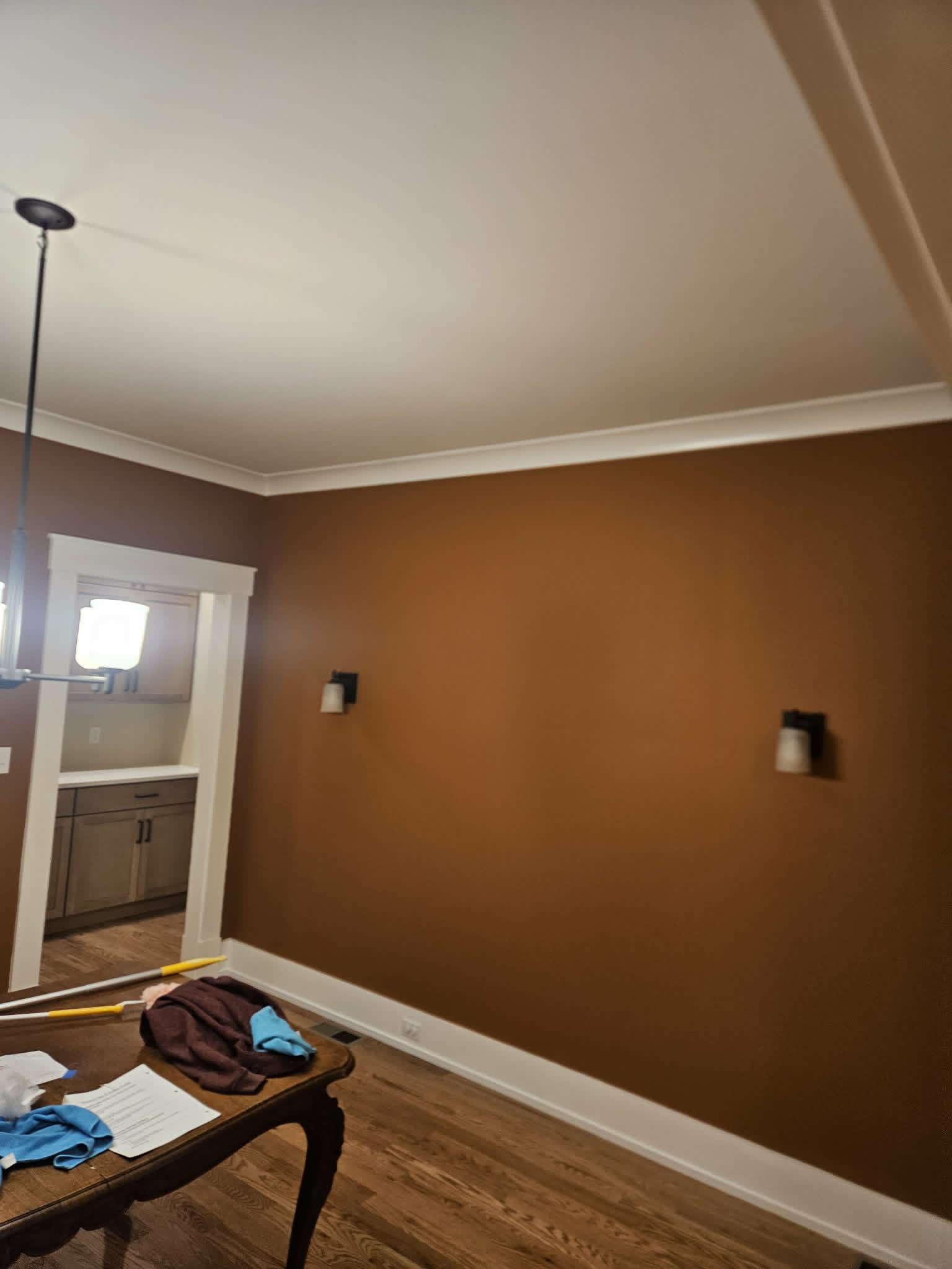 Dining room feature wall in a rich copper tone framed by crisp white crown moulding and trim — interior painting with a smooth finish.