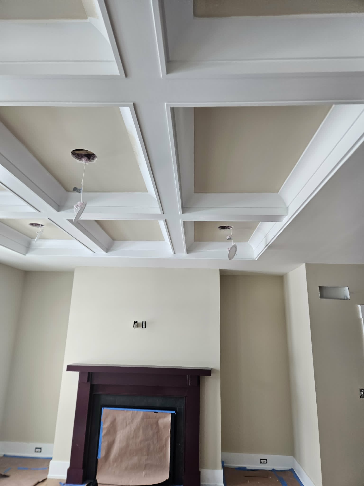 Warm beige room crowned by a white coffered ceiling with a dark stained fireplace mantel — interior painting and detailed trim work.
