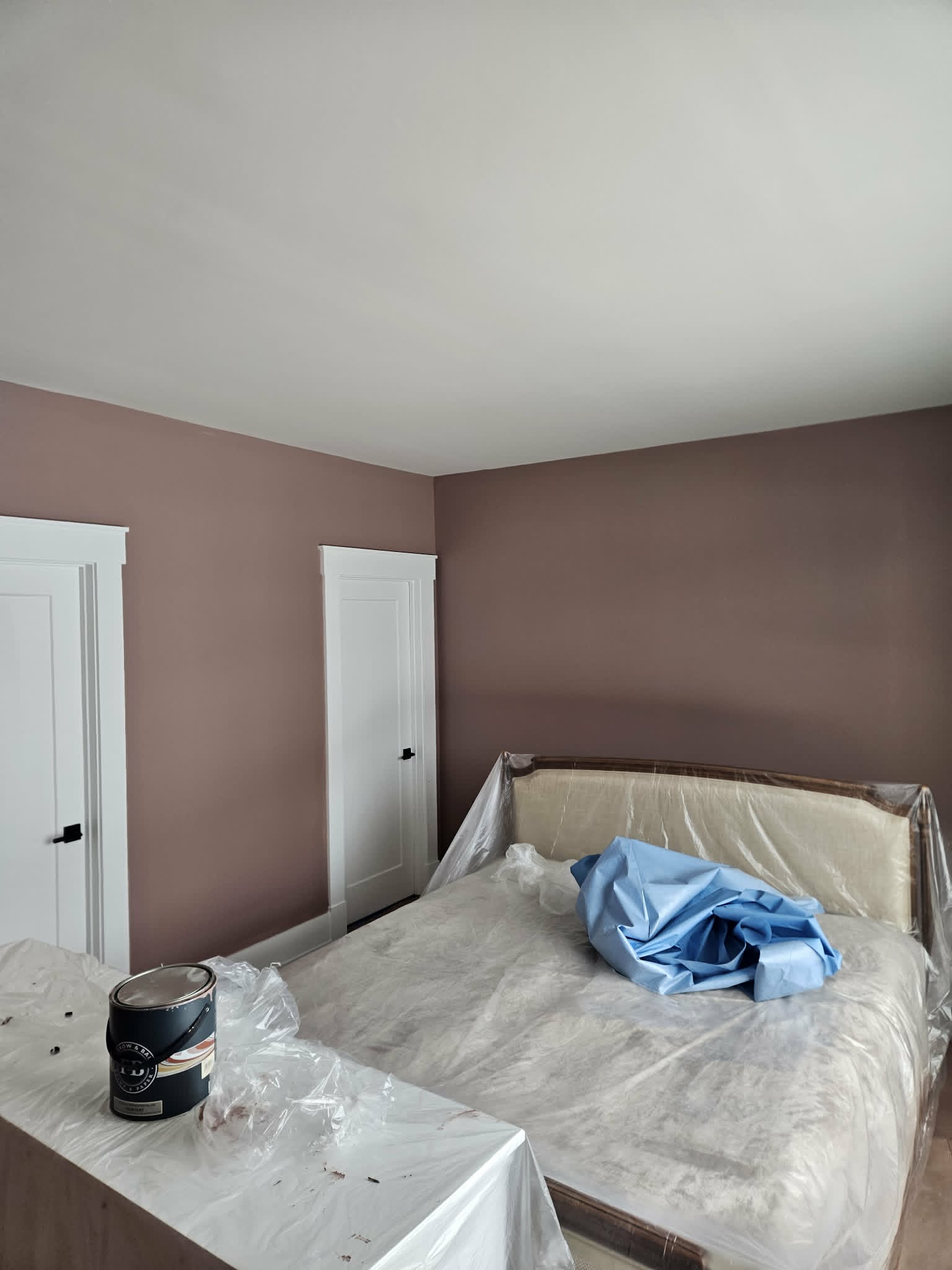 Bedroom with warm dusty-rose walls, a bright white ceiling and freshly painted doors and trim — interior painting with a smooth finish.