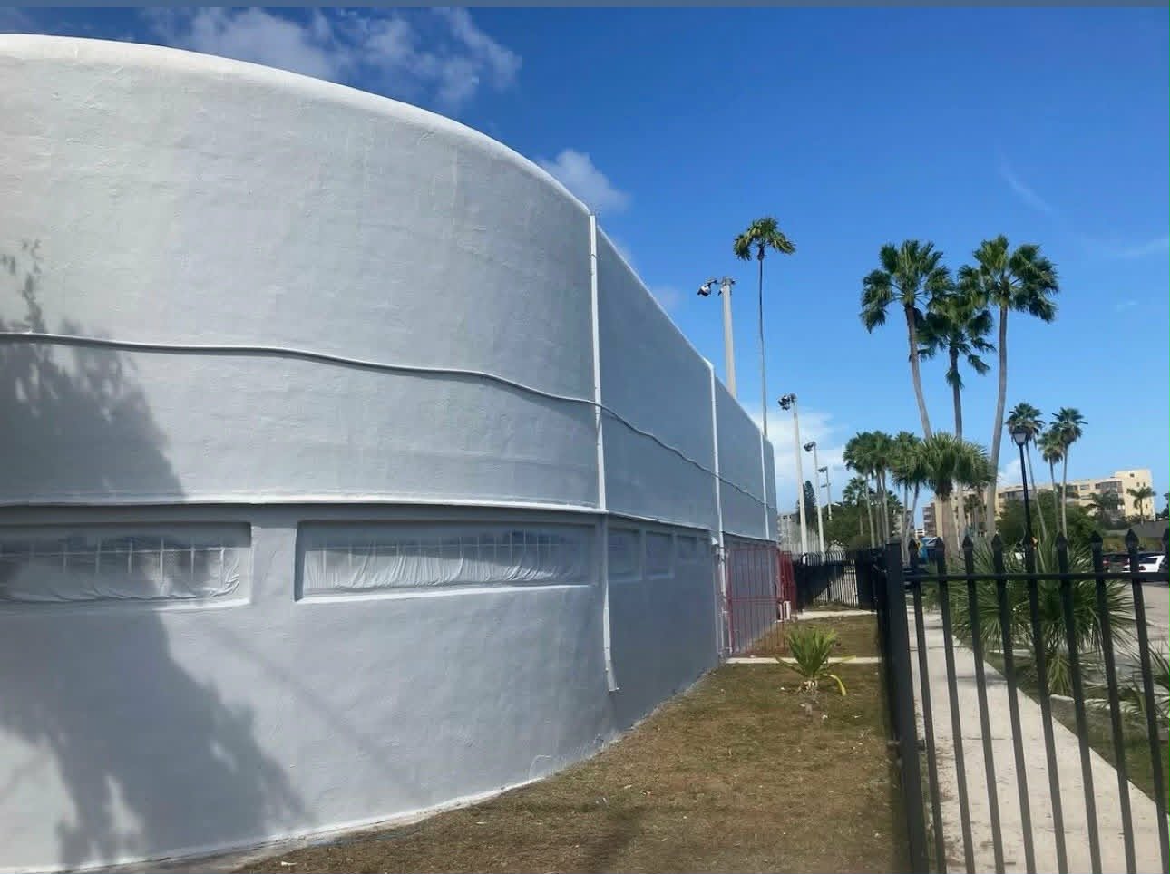 Large curved commercial building exterior freshly coated in a clean, uniform white — full-scale commercial exterior painting.