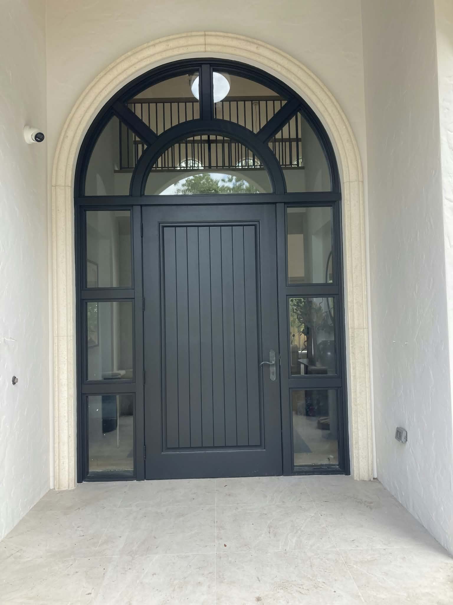 Arched entryway door freshly painted in a deep charcoal tone. — entry door painting, exterior door finish, charcoal door paint